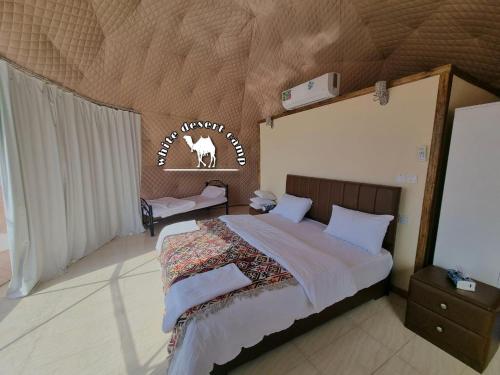 a bedroom with a bed with a cow sign on the wall at White Desert Camp in Wadi Rum