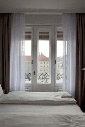 a bedroom with a bed and two windows at Premium Apartment by Hi - Central 2 BR - best view in Budapest