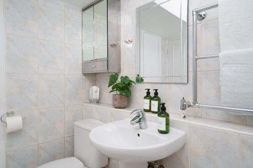 a bathroom with a sink and a toilet and a mirror at Best Location Oxford Str, Soho 2 Bedr, 3 Beds, 2 Bath in London