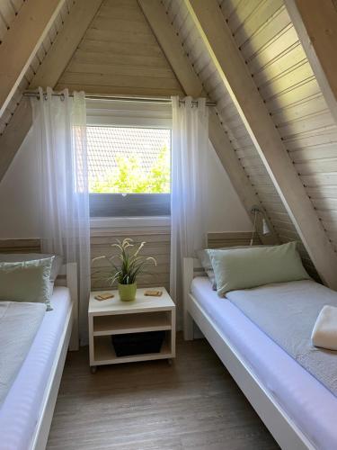 Schlafzimmer im Dachgeschoss mit 2 Betten und einem Fenster in der Unterkunft Murmel 1 - Strandkorb, Wallbox, WLan, Kamin in Carolinensiel