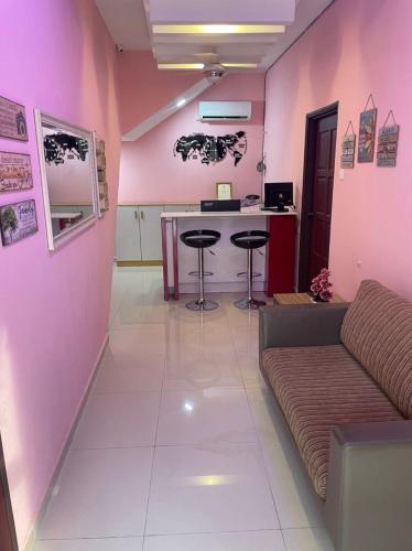 a living room with pink walls and a couch and a counter at A&H HOUSE HOTEL in Melaka