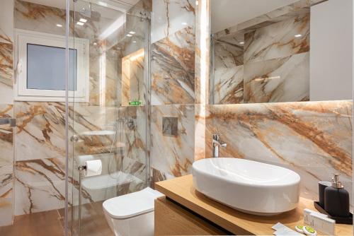 La salle de bains est pourvue d'un lavabo, de toilettes et d'une douche. dans l'établissement Acropolis Holmes Residence, à Athènes