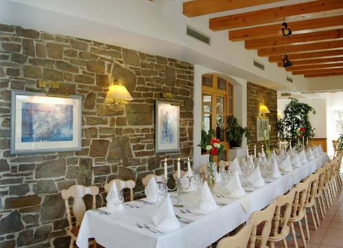 Waldhotel Forsthaus Remstecken في كوبلنز: طاولة طويلة مع طاولات بيضاء وكراسي في جدار حجري