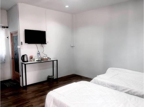 a bedroom with two beds and a tv on the wall at Capital O 75412 V Resort in Nakhon Nayok