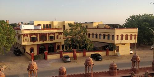 Un gran edificio con coches aparcados delante. en Sankhu Niwas, en Bikaner