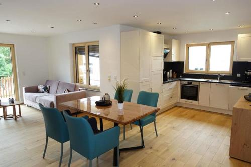 a kitchen and living room with a wooden table and blue chairs at Ferienwohnung Chalet Marienbrunnen in Oberstaufen