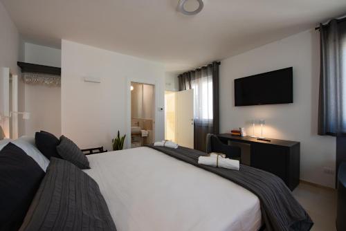 a bedroom with a large white bed and a flat screen tv at Suite1212 - Rattazzi in Monopoli