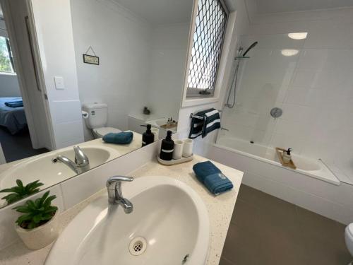 Baño blanco con lavabo y bañera en Cozy townhouse in Dakabin ideal for young family, en Kallangur
