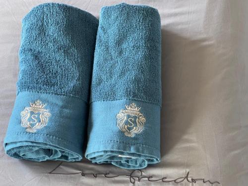 two blue towels with a crest on them on a bed at Cozy townhouse in Dakabin ideal for young family in Kallangur