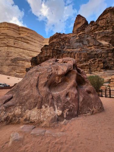 a large rock in the desert with mountains in the background at White Desert Camp in Wadi Rum