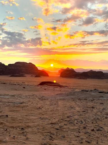 a sunset in the desert with the sun setting at White Desert Camp in Wadi Rum