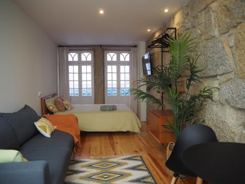 a living room with a bed and a stone wall at Casa Farrapos in Porto