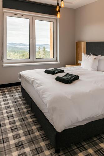 a large white bed with two black towels on it at Kazalnica Family&Conference Resort in Karpacz