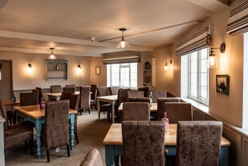 a dining room with tables and chairs and windows at The Thorold in Marston