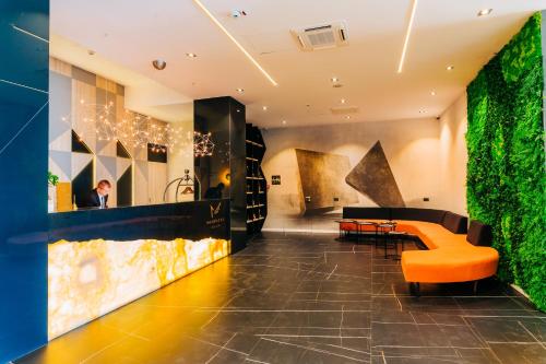 a lobby with an orange couch and a green wall at Mandachi Hotel & SPA in Suceava