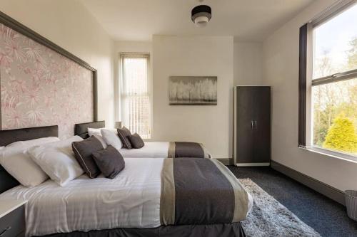 1 dormitorio con 2 camas y ventana grande en Midwood Lodge, en Mánchester