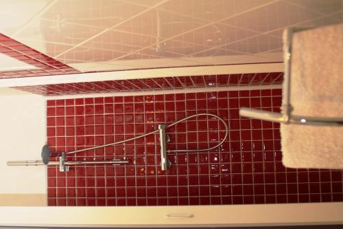a red tiled wall in a bathroom with a tennis racket at B&B Tra Monti e Mare in Ogliastro Cilento