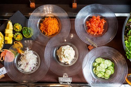 four bowls of food on a counter with vegetables at Daiwa Roynet Hotel Okinawa-Kenchomae in Naha