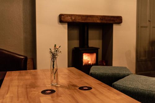 a vase of flowers on a wooden table with a fireplace at The Thorold in Marston