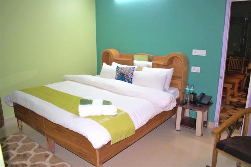 1 dormitorio con 1 cama grande y paredes verdes en Prairie Lodge en Shimla