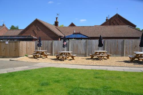 a group of picnic tables and umbrellas in front of a fence at The Thorold in Marston