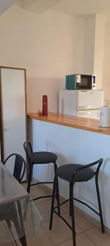 a kitchen with two chairs and a counter with a microwave at Sol y Malbec Departamentos in Guaymallen