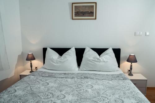 ein Schlafzimmer mit einem Bett mit weißen Kissen und zwei Lampen in der Unterkunft Bessemer in Wien