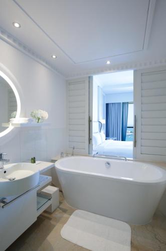 a white bathroom with a large tub and a sink at Sofitel Dubai Jumeirah Beach in Dubai