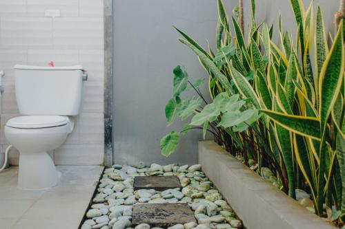 a bathroom with a toilet and a bunch of plants at Shrining Cottages Lembongan in Nusa Lembongan