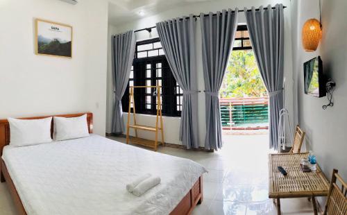 a bedroom with a bed and a large window at NẮNG HOMESTAY in Tuy Hoa