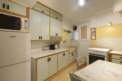 eine Küche mit weißen Schränken und einer Mikrowelle in der Unterkunft Prime Location 2 BR APT next to the Acropolis in Athen