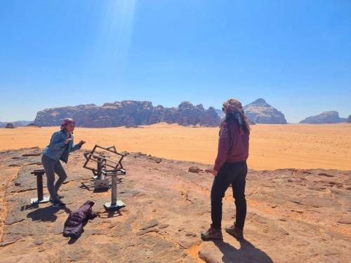 two people standing next to a machine in the desert at White Desert Camp in Wadi Rum