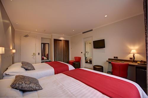 a hotel room with two beds and a desk at Hôtel Du Midi Paris Montparnasse in Paris