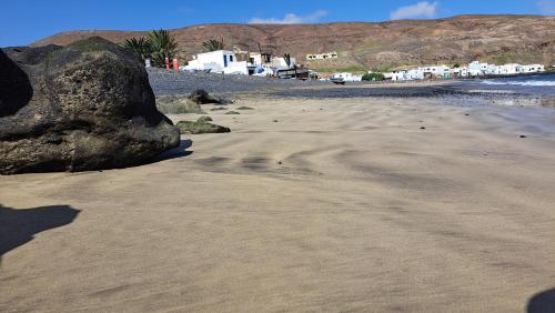 a rock on a sandy beach with footprints in the sand at Mar de Lava Sunrise Fuerteventura in Pozo Negro