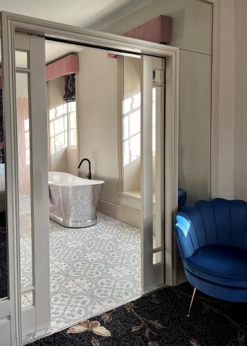 a bathroom with a tub and a blue chair at The Haycock Manor Hotel in Wansford