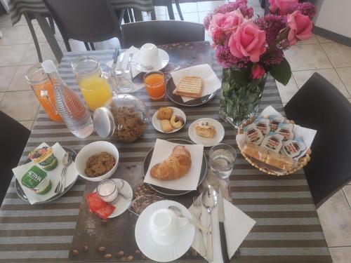 een tafel met ontbijtproducten en een vaas met bloemen bij B&B Menna Vence in Zumpano