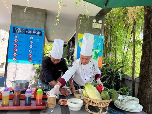 two men in chefs hats preparing food on a table at Bayon Modern Residence in Siem Reap
