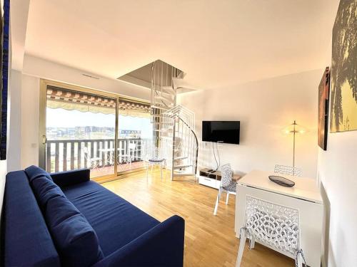 ein Wohnzimmer mit einem blauen Sofa und einem Balkon in der Unterkunft Le Castel 1 C.L.S Deauville in Deauville