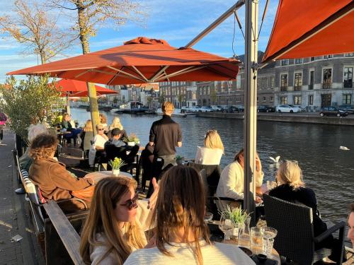 a group of people sitting at a restaurant by the water at GuesthouseOne in Haarlem