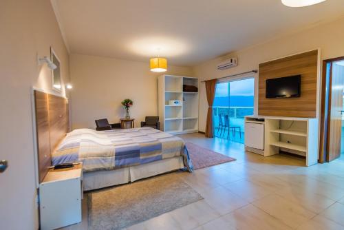 a bedroom with a bed and a television and a desk at Hotel Fazenda Dona Francisca in Joinville