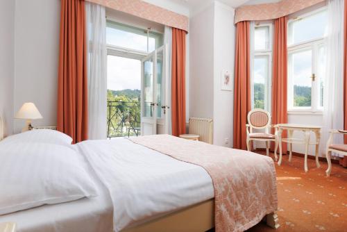 a bedroom with a bed and a large window at OREA Spa Hotel Palace Zvon Mariánské Lázně in Mariánské Lázně
