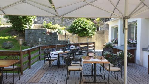 a patio with tables and chairs under an umbrella at Hotel Filli in Scuol