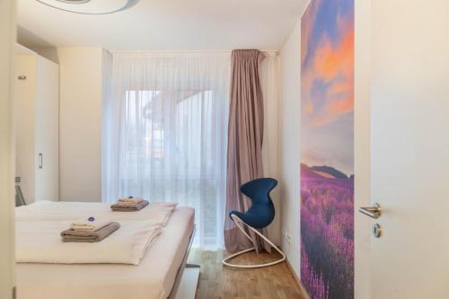 een slaapkamer met een bed, een raam en een blauwe stoel bij Apartment zum Genießen in Garmisch-Partenkirchen