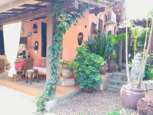 a house with a green ivy covered porch with potted plants at Vila Santa Rosa Guest House in Ilhabela