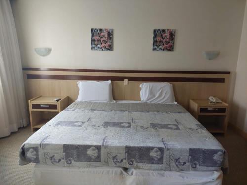 ブラジリアにあるLets Idea Hotel Flat Particularのベッドルーム1室(大型ベッド1台、ナイトスタンド2台付)
