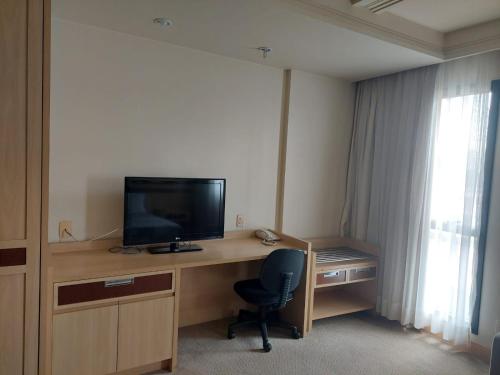 a room with a desk with a television and a chair at Lets Idea Hotel Flat Particular in Brasilia