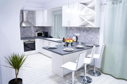 a kitchen with white cabinets and a table and chairs at SunStone Apartment in Fira