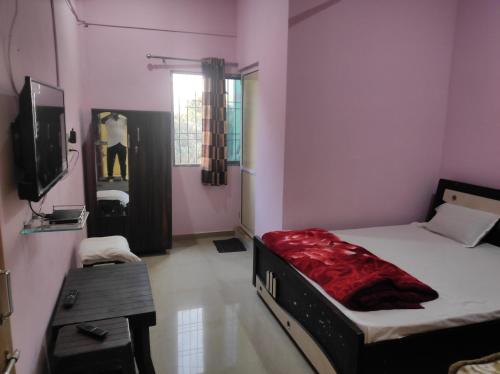 a room with a bed and a tv in it at Vrundavan home stay and Village resort in Kevadia