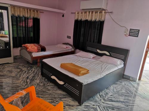 two beds in a room with an orange chair at Vrundavan home stay and Village resort in Kevadia