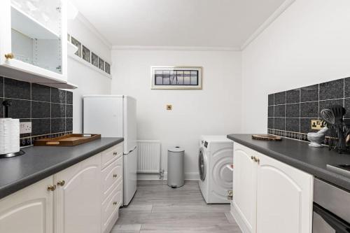 een keuken met witte apparatuur en zwarte tegels bij One bedroom duplex apartment located in cowley. in Oxford